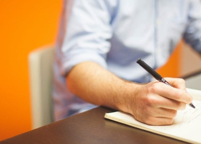 man writing in notebook